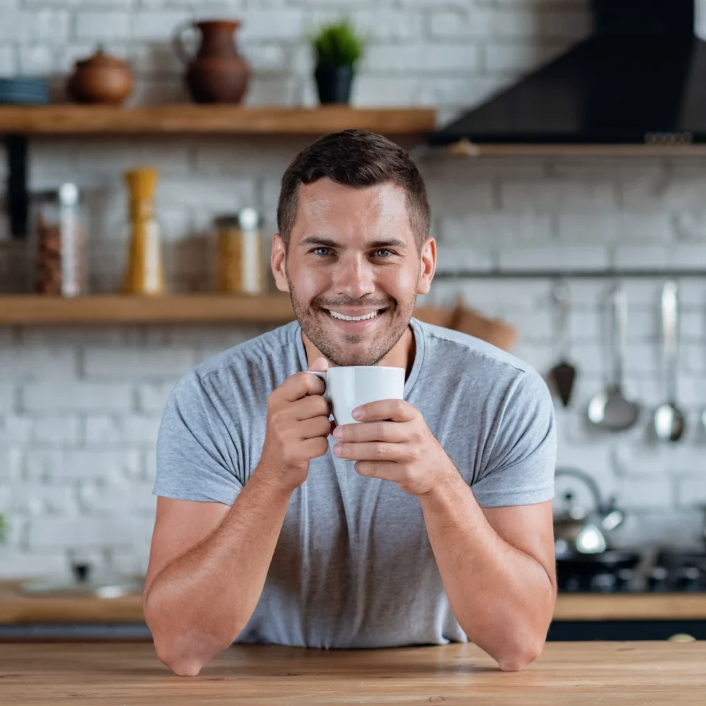 man smiling with cup of coffee after professional teeth whitening